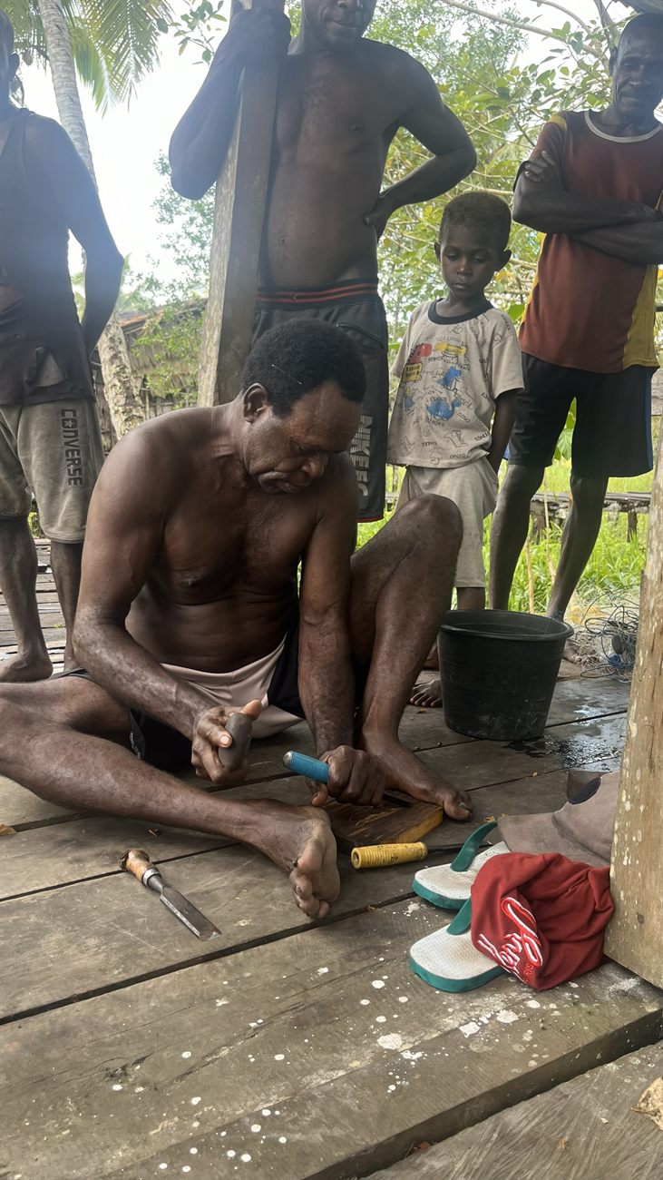 Asmat woodcarver shaping wood by hand